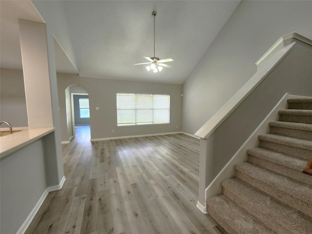2623 Sable Ridge Ln, Katy, TX 77494 - unfurnished living room with a ceiling fan, arched walkways, light wood-style floors, stairs, and high vaulted ceiling