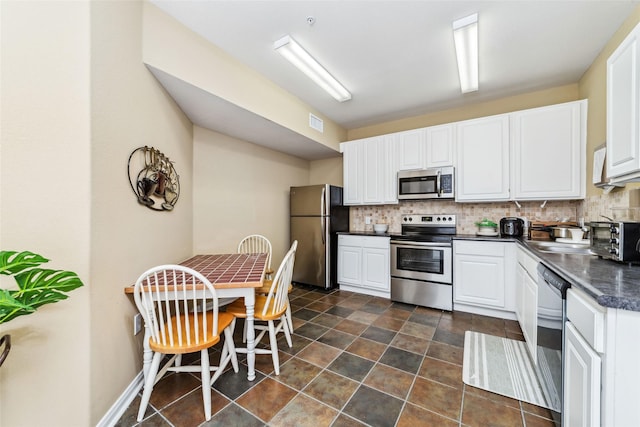 2815 Kings Crossing Dr Unit 106, Houston, TX 77345 - kitchen with appliances with stainless steel finishes, dark countertops, tasteful backsplash, white cabinets, and baseboards