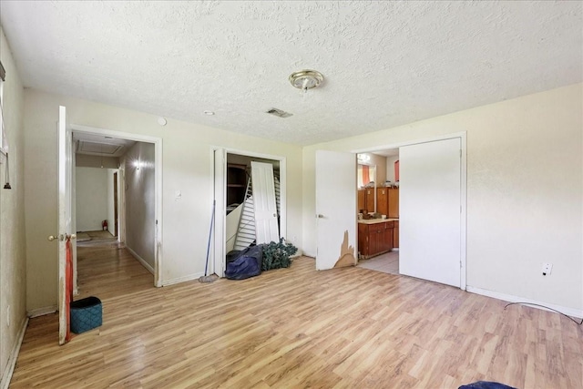 2630 35th St, Pinehurst, TX 77630 - unfurnished bedroom with attic access, light wood-style flooring, a textured ceiling, baseboards, and a closet