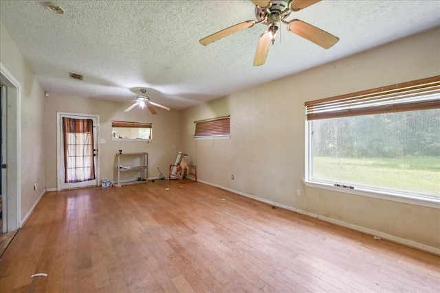 2630 35th St, Pinehurst, TX 77630 - unfurnished living room featuring a ceiling fan, hardwood / wood-style flooring, a textured ceiling, and baseboards