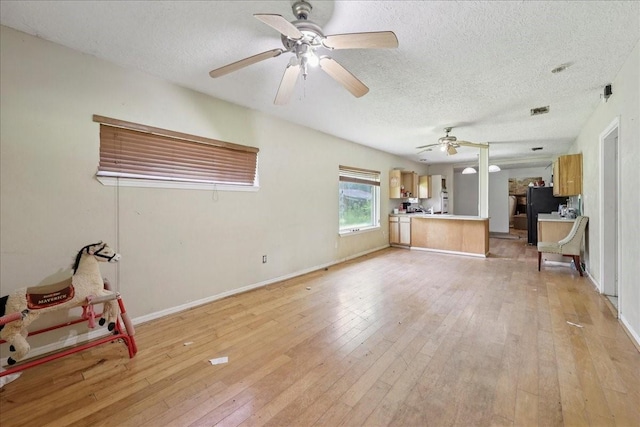 2630 35th St, Pinehurst, TX 77630 - unfurnished living room with ceiling fan, a textured ceiling, light wood-type flooring, and baseboards