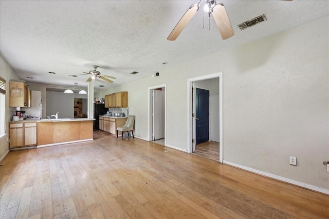 2630 35th St, Pinehurst, TX 77630 - unfurnished living room featuring ceiling fan, a textured ceiling, light wood-style flooring, and baseboards