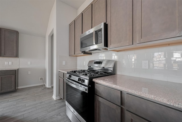 3235 Owl Hollow Dr, Rosenberg, TX 77471 - kitchen featuring appliances with stainless steel finishes, light stone countertops, tasteful backsplash, light wood finished floors, and vaulted ceiling