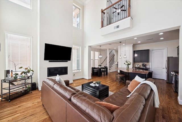 2619 Shady Woods Ln, Houston, TX 77008 - living area featuring stairway, a high ceiling, wood finished floors, crown molding, and a glass covered fireplace