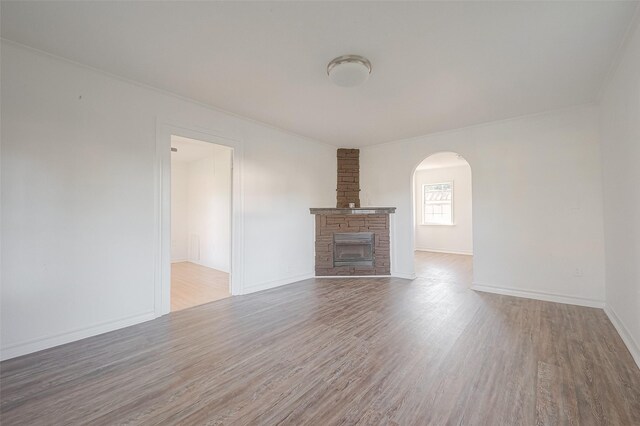 607 Speed St, Wharton, TX 77488 - unfurnished living room with wood finished floors, arched walkways, a fireplace, and baseboards