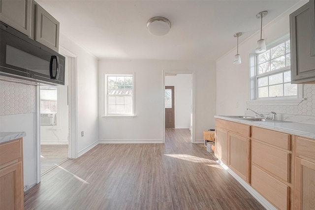 607 Speed St, Wharton, TX 77488 - kitchen featuring a sink, black microwave, light wood-type flooring, light countertops, and backsplash