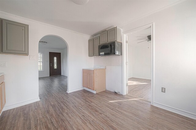 607 Speed St, Wharton, TX 77488 - unfurnished living room with arched walkways, wood finished floors, crown molding, ceiling fan, and baseboards