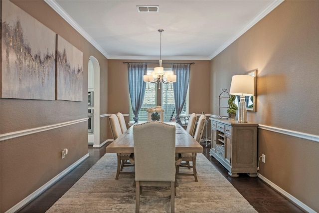 2978 Vintage Park Ln, Pearland, TX 77584 - dining area featuring dark wood finished floors, a chandelier, arched walkways, baseboards, and crown molding