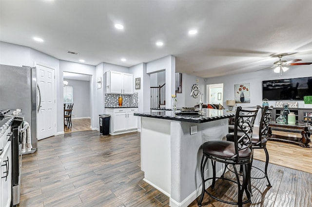 14203 Coveney Dr, Houston, TX 77090 - kitchen featuring a breakfast bar area, a ceiling fan, white cabinets, dark wood-type flooring, and recessed lighting