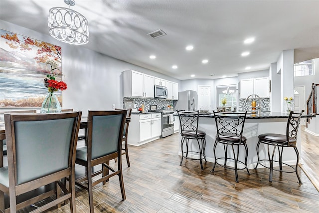14203 Coveney Dr, Houston, TX 77090 - kitchen featuring appliances with stainless steel finishes, a kitchen breakfast bar, decorative backsplash, light wood-style flooring, and recessed lighting