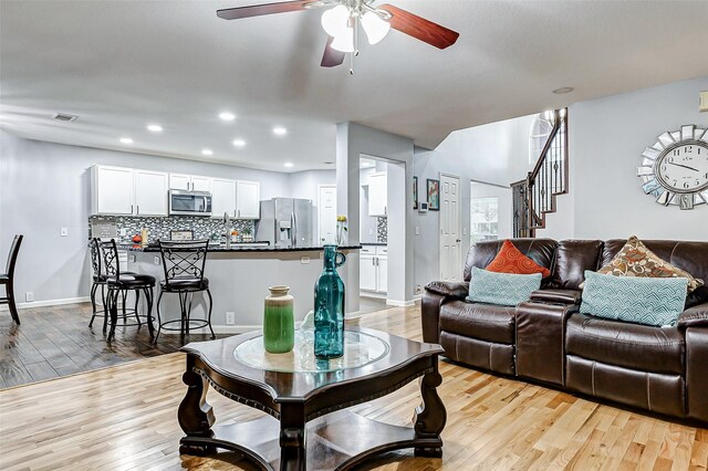 14203 Coveney Dr, Houston, TX 77090 - living room featuring a ceiling fan, light wood-type flooring, recessed lighting, stairway, and baseboards