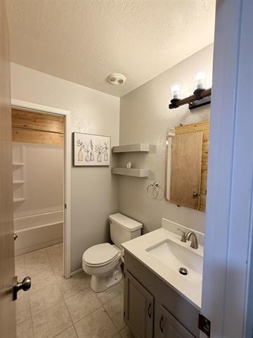 9410 Guy Cir, Beaumont, TX 77707 - bathroom featuring vanity, toilet, a textured ceiling, and tile patterned floors