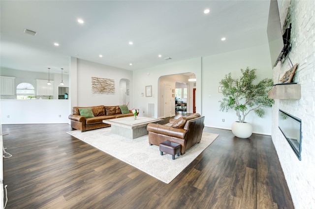 6219 Mound Airy Ct, Sugar Land, TX 77479 - living area featuring arched walkways, dark wood-style floors, a large fireplace, recessed lighting, and plenty of natural light