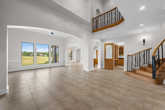 504 High Meadow Ranch Dr, Magnolia, TX 77355 - unfurnished living room with arched walkways, a high ceiling, stairway, crown molding, and recessed lighting