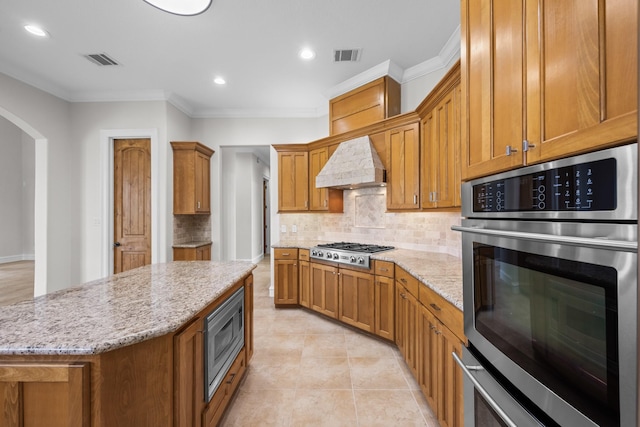 504 High Meadow Ranch Dr, Magnolia, TX 77355 - kitchen with stainless steel appliances, backsplash, ornamental molding, light stone counters, and a center island