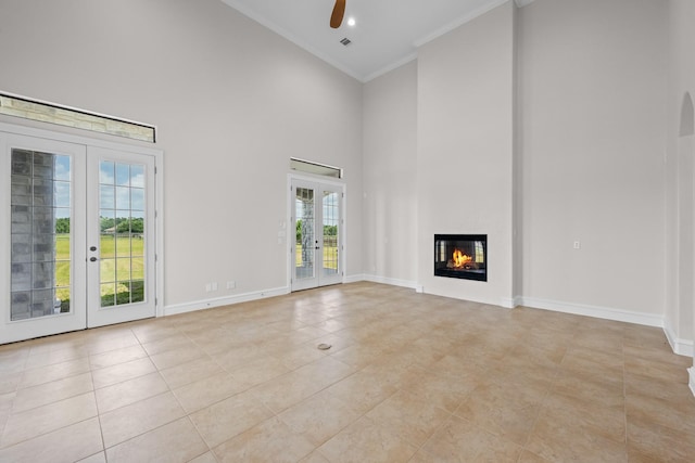 504 High Meadow Ranch Dr, Magnolia, TX 77355 - unfurnished living room with french doors, a towering ceiling, ceiling fan, crown molding, and a glass covered fireplace