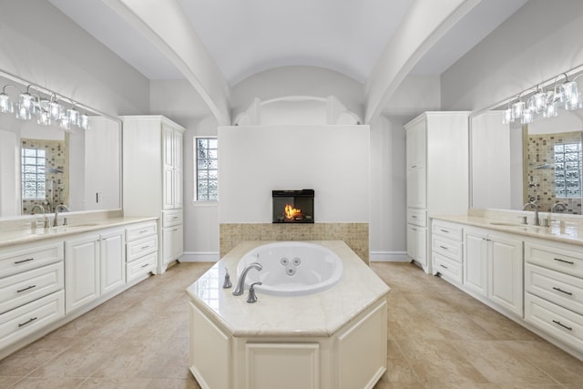504 High Meadow Ranch Dr, Magnolia, TX 77355 - full bath featuring two vanities, a whirlpool tub, vaulted ceiling, a multi sided fireplace, and plenty of natural light