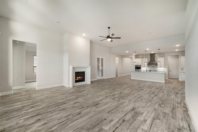 17020 Sweet Iris Ct, Conroe, TX 77302 - unfurnished living room with a ceiling fan, light wood-style floors, a lit fireplace, baseboards, and recessed lighting