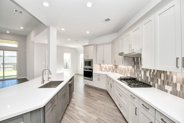 20922 Whirlaway Green Cir, Tomball, TX 77377 - kitchen featuring stainless steel appliances, a sink, under cabinet range hood, light countertops, and light wood-type flooring