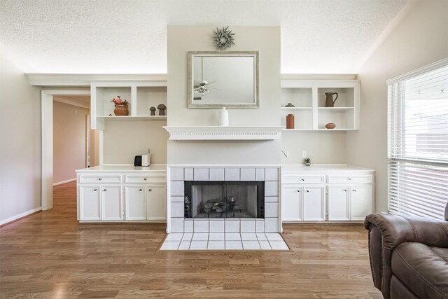 4222 Skylane Rd, Beach City, TX 77523 - living area featuring light wood-style floors, a tiled fireplace, and a textured ceiling