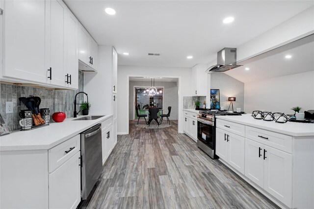 5702 Indigo St, Houston, TX 77096 - kitchen with island exhaust hood, appliances with stainless steel finishes, decorative backsplash, light countertops, and a peninsula