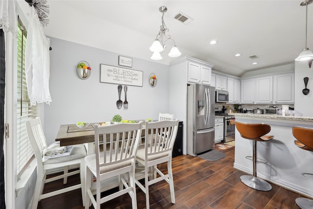 10025 Jason Ct, Beaumont, TX 77705 - kitchen with appliances with stainless steel finishes, dark wood finished floors, decorative light fixtures, a kitchen breakfast bar, and white cabinets