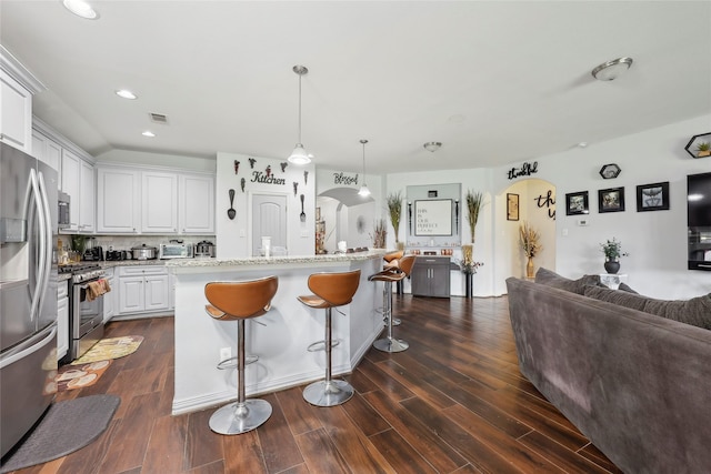 10025 Jason Ct, Beaumont, TX 77705 - kitchen with appliances with stainless steel finishes, arched walkways, a breakfast bar area, white cabinetry, and dark wood-style floors