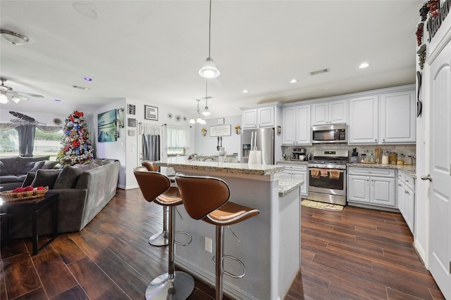 10025 Jason Ct, Beaumont, TX 77705 - kitchen featuring appliances with stainless steel finishes, open floor plan, dark wood finished floors, light stone counters, and recessed lighting