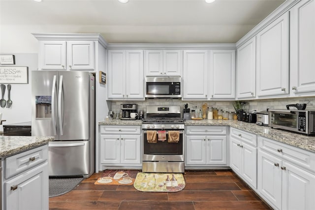 10025 Jason Ct, Beaumont, TX 77705 - kitchen featuring appliances with stainless steel finishes, recessed lighting, decorative backsplash, dark wood-style flooring, and white cabinetry