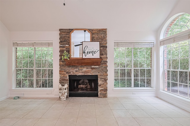 26 Skyland Pl, The Woodlands, TX 77381 - unfurnished living room featuring vaulted ceiling, tile patterned floors, a stone fireplace, and healthy amount of natural light