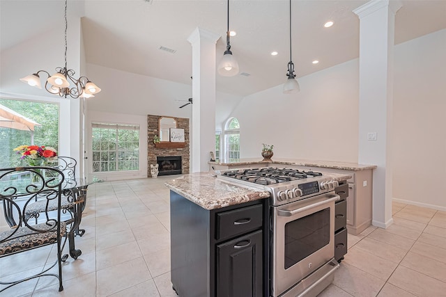 26 Skyland Pl, The Woodlands, TX 77381 - kitchen featuring stainless steel gas range, light tile patterned floors, a fireplace, vaulted ceiling, and dark cabinetry