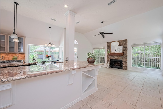 26 Skyland Pl, The Woodlands, TX 77381 - kitchen featuring a ceiling fan, light tile patterned flooring, lofted ceiling, light stone countertops, and backsplash