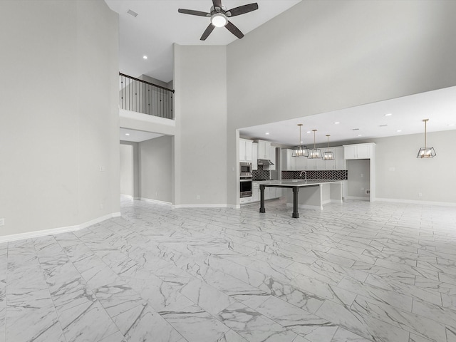 2107 Jitterbug Ln, Katy, TX 77493 - unfurnished living room with light marble finish flooring, a ceiling fan, baseboards, a towering ceiling, and recessed lighting