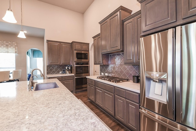 13326 Hartford Bay Trl, Cypress, TX 77429 - kitchen featuring appliances with stainless steel finishes, arched walkways, light countertops, dark wood-style flooring, and backsplash