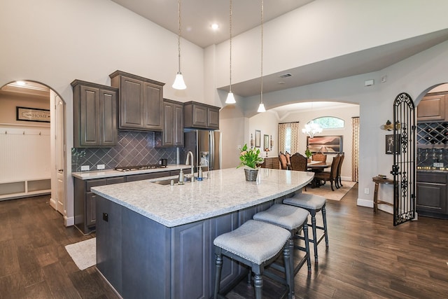13326 Hartford Bay Trl, Cypress, TX 77429 - kitchen featuring stainless steel fridge with ice dispenser, arched walkways, high vaulted ceiling, an island with sink, and dark wood-type flooring