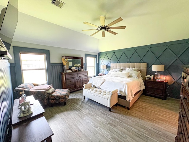 2900 Green Ash Ct, Conroe, TX 77301 - bedroom with multiple windows, wood finished floors, vaulted ceiling, wainscoting, and a decorative wall