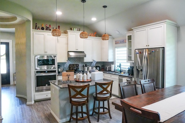 2900 Green Ash Ct, Conroe, TX 77301 - kitchen featuring stainless steel appliances, under cabinet range hood, decorative backsplash, wood finished floors, and a kitchen island