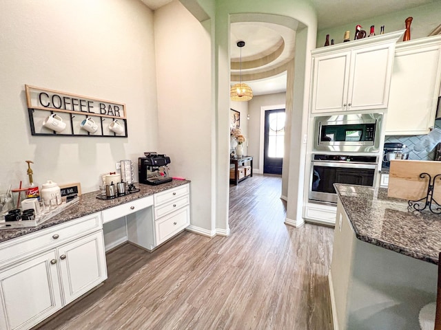 2900 Green Ash Ct, Conroe, TX 77301 - kitchen featuring appliances with stainless steel finishes, light wood-style flooring, dark stone counters, and white cabinetry