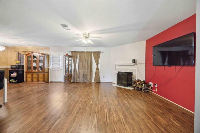 8202 Caddo Rd, Houston, TX 77078 - unfurnished living room featuring a tiled fireplace, a ceiling fan, and wood finished floors