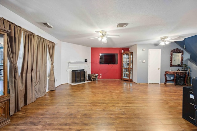 8202 Caddo Rd, Houston, TX 77078 - unfurnished living room featuring a ceiling fan, wood finished floors, a fireplace, and a textured ceiling