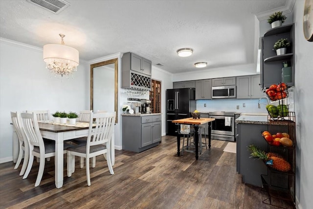 8307 Parasol Ln, Houston, TX 77064 - kitchen with stainless steel appliances, gray cabinets, crown molding, dark wood finished floors, and a chandelier