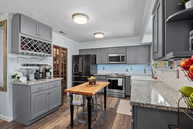 8307 Parasol Ln, Houston, TX 77064 - kitchen with appliances with stainless steel finishes, gray cabinets, crown molding, dark wood-style floors, and a textured ceiling