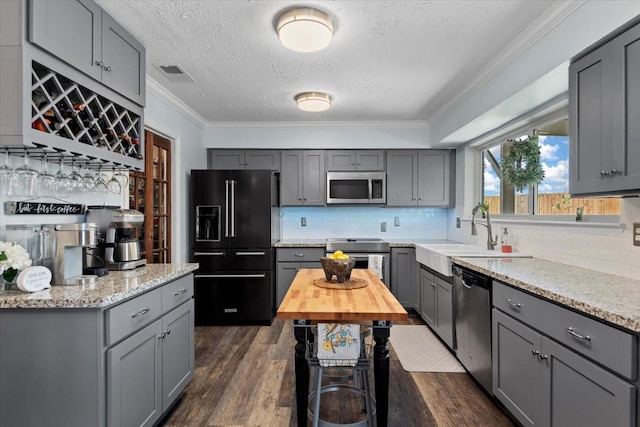 8307 Parasol Ln, Houston, TX 77064 - kitchen featuring appliances with stainless steel finishes, gray cabinetry, crown molding, a textured ceiling, and dark wood-type flooring