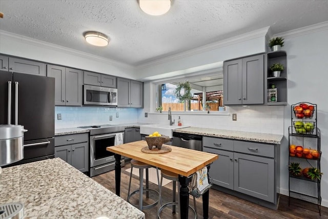 8307 Parasol Ln, Houston, TX 77064 - kitchen with appliances with stainless steel finishes, gray cabinets, a sink, dark wood finished floors, and crown molding