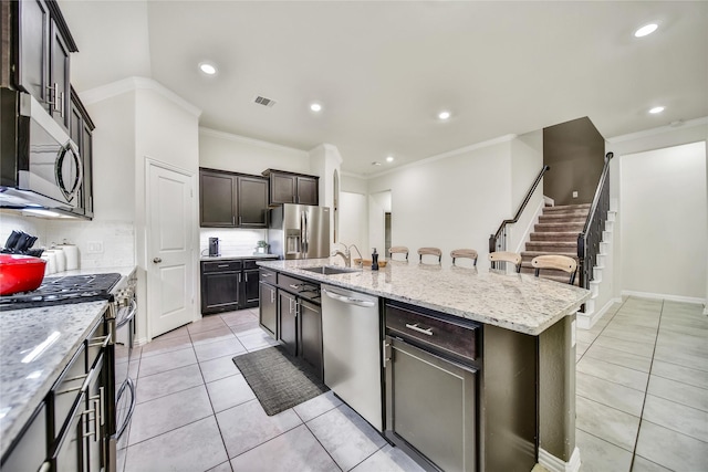 7411 Nottington Ct, Spring, TX 77379 - kitchen with appliances with stainless steel finishes, crown molding, light tile patterned floors, tasteful backsplash, and a center island with sink