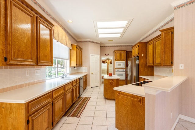 2107 Enchanted Lake Dr, League City, TX 77573 - kitchen with appliances with stainless steel finishes, brown cabinetry, a sink, backsplash, and crown molding
