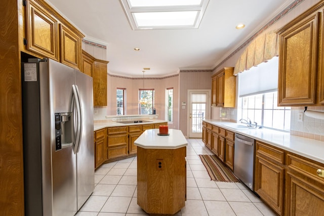 2107 Enchanted Lake Dr, League City, TX 77573 - kitchen featuring stainless steel appliances, brown cabinets, a sink, a peninsula, and ornamental molding