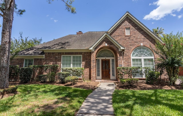 2107 Enchanted Lake Dr, League City, TX 77573 - view of front of house with brick siding, a front lawn, a chimney, and a shingled roof