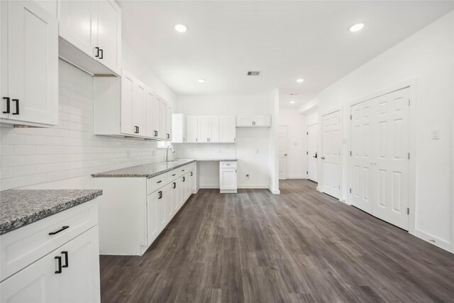 5608 Hollow Pines Dr, Houston, TX 77049 - kitchen with dark wood-style flooring, light stone counters, white cabinetry, recessed lighting, and decorative backsplash