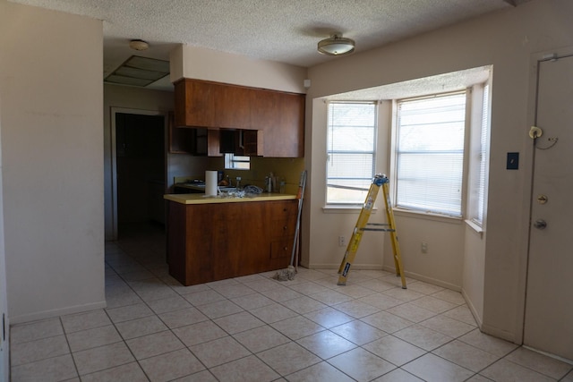 702 Meadowglen Dr, Baytown, TX 77521 - kitchen with light countertops, a textured ceiling, brown cabinetry, and light tile patterned floors